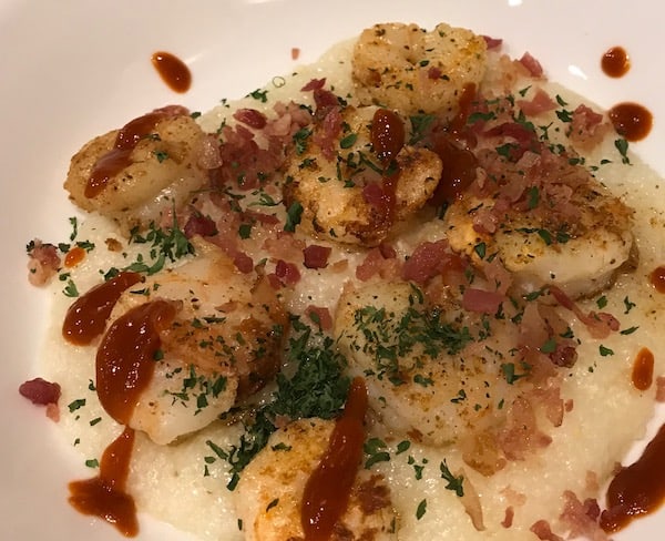 Shrimp and grits with crumbled bacon, parsley, and sriracha