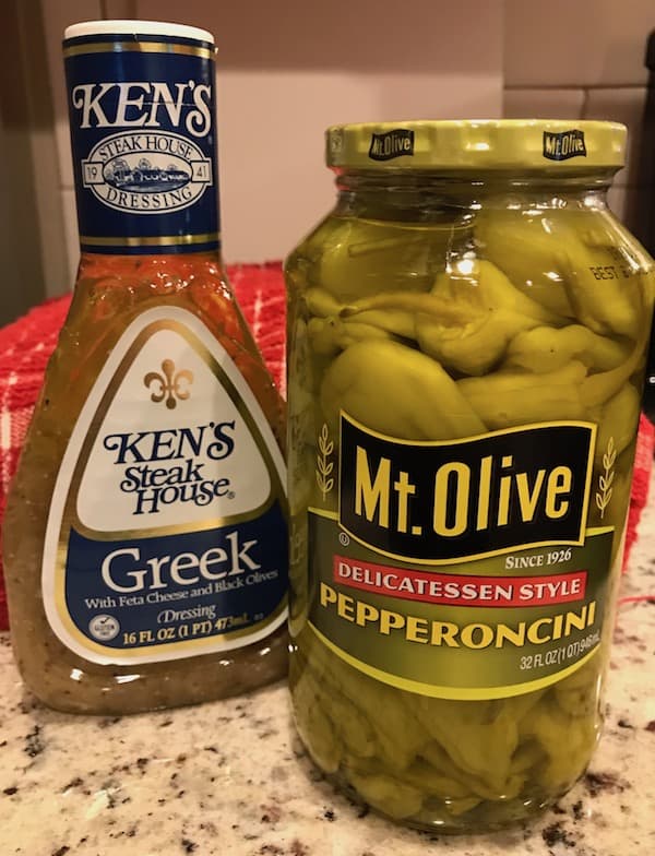 Bottle of Greek salad dressing and jar of pepperoncini