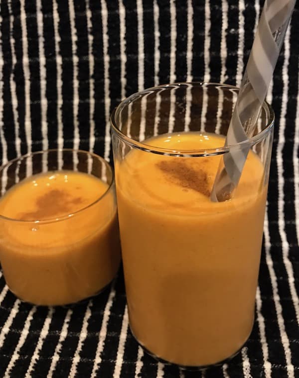 Two pumpkin smoothies sprinkled with cinnamon, one with a large straw