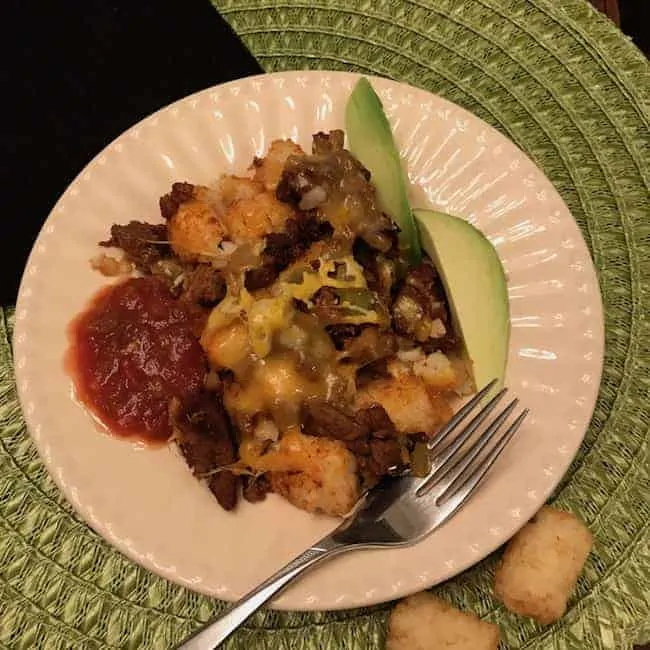 Tater Tot taco casserole with slices of avocado and salsa