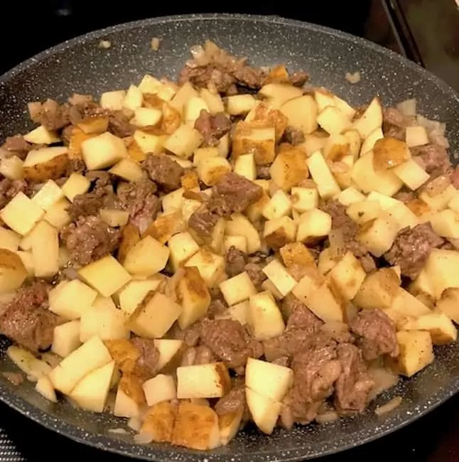 Beef, onions, and potatoes in a skillet