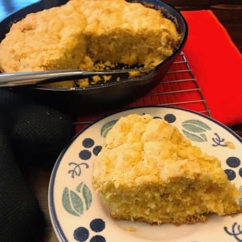 Slice of cracklin' cornbread next to a skillet of cornbread