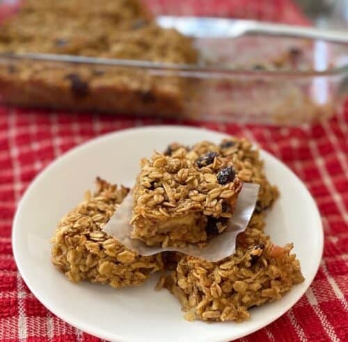 Apple raisin oat bars on a plate in front of a pan