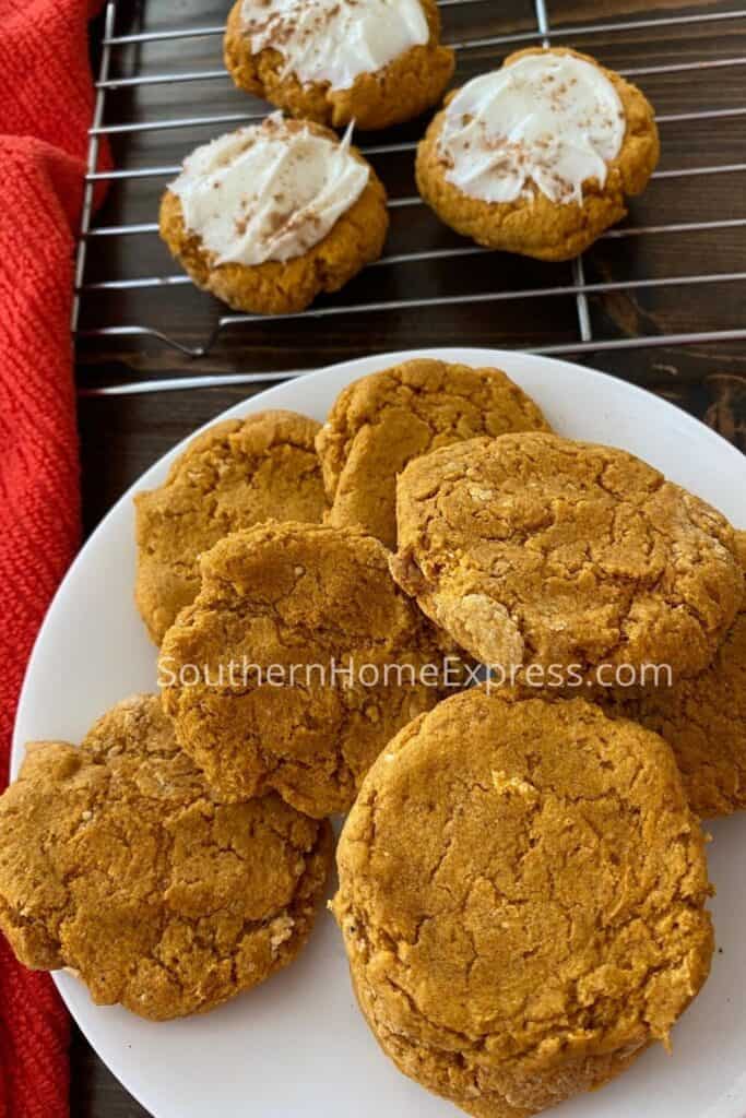 Platter of pumpkin cookies beside a cooling rack with more cookies