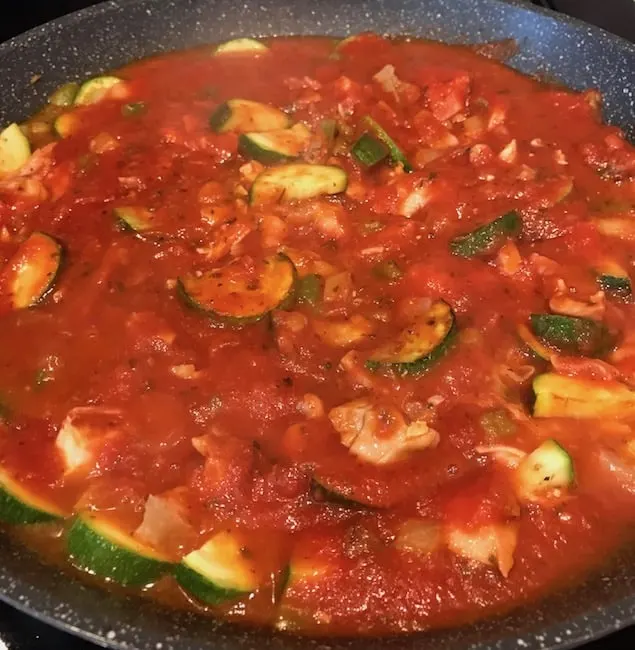 Italian sauce, zucchini, chicken, peppers, and onions in a pan