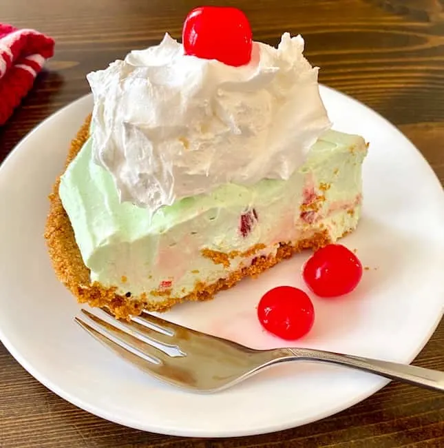 Slice of cherry lime pie with whipped cream and a cherry