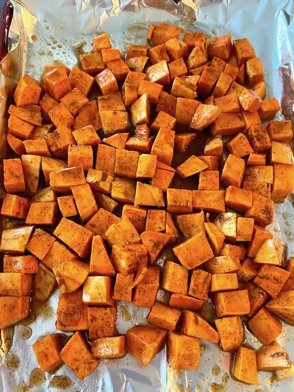 Uncooked coated sweet potatoes on a baking sheet