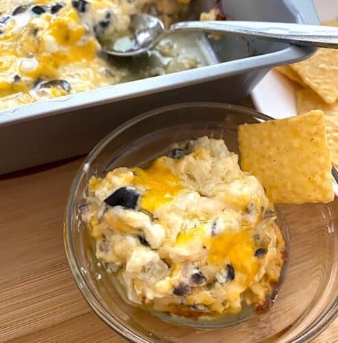 pan and bowl of cheesy olive dip with crackers