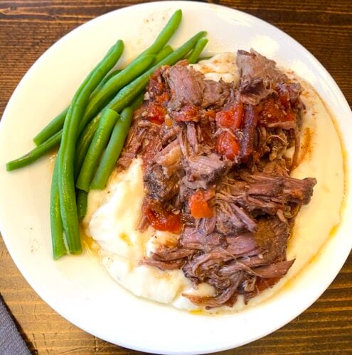 garlic tomato roast on mashed potatoes beside steamed green beans