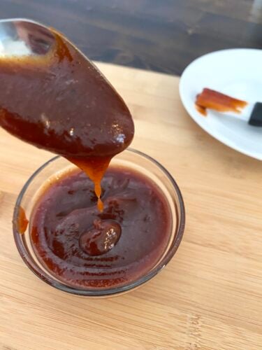 spooning barbecue sauce over a bowl