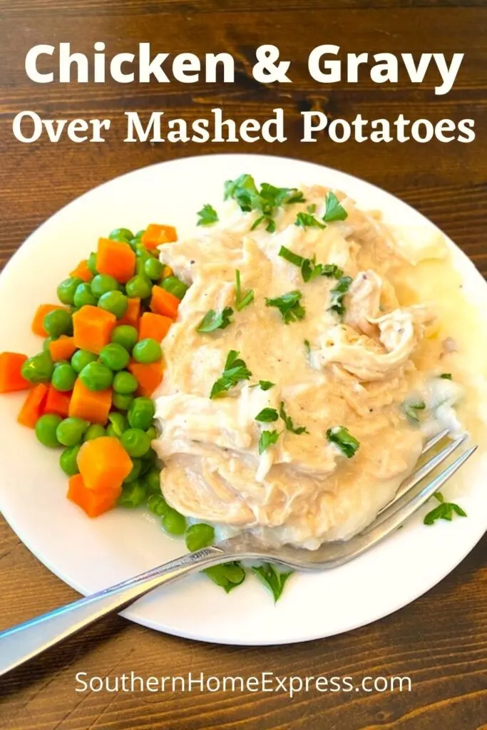 plate of chicken and gravy with a side of peas and carrots