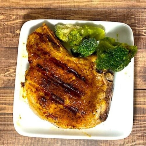 grilled pork chop on a plate with broccoli