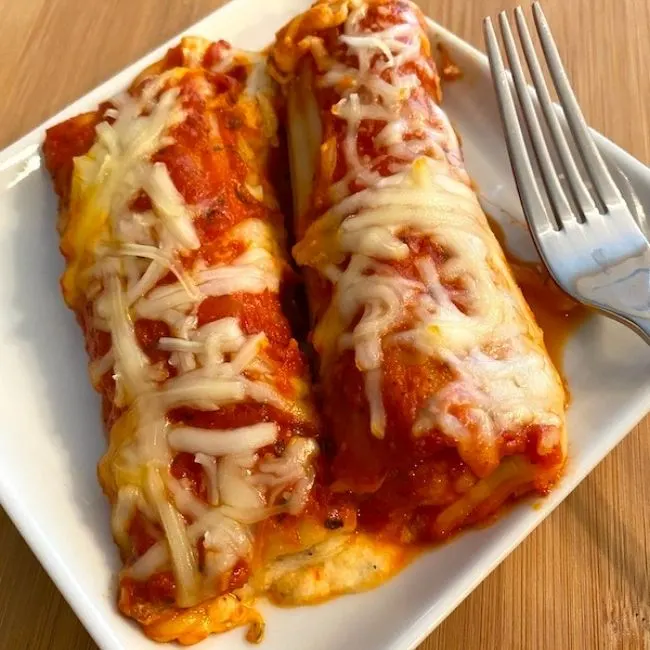 2 stuffed manicotti shells with melted cheese on top