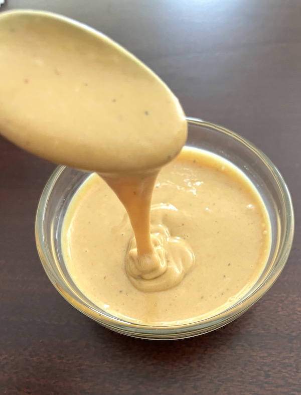 drizzling Chick Fil A sauce with a spoon over a small bowl