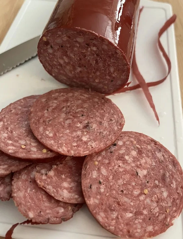 cutting summer sausage on cutting board