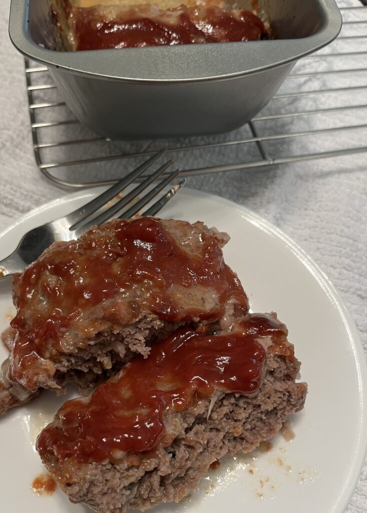 slices of meatloaf on a plate beside a pan of meatloaf