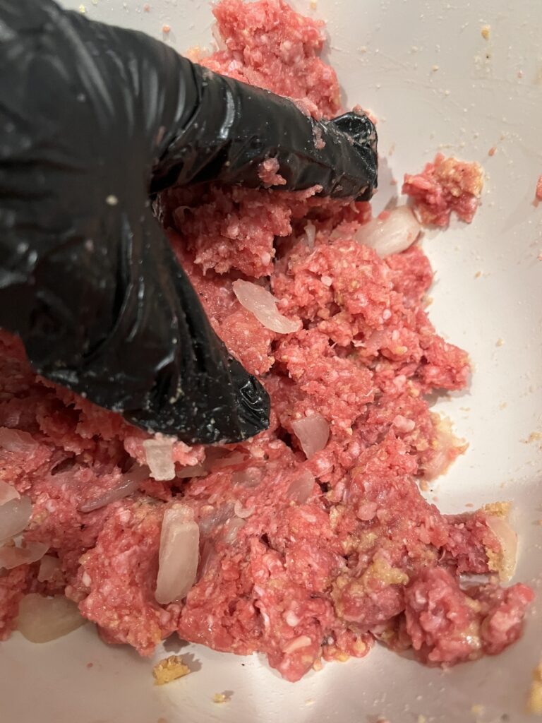 gloved hand mixing meatloaf ingredients