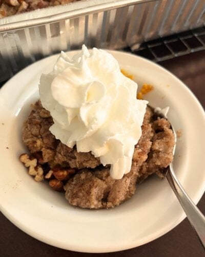 bowl of pumpkin pecan cobbler topped with whipped cream