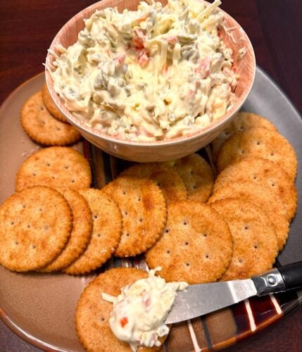 bowl of spanish olive spread with a platter of crackers