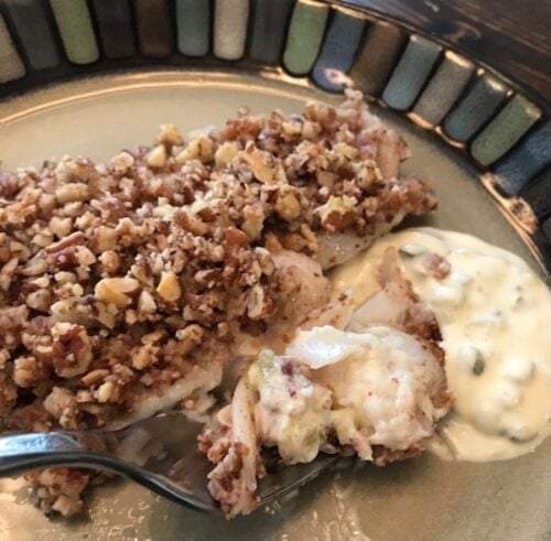 plated pecan crusted fish with a forkful of it hovering over tartar sauce