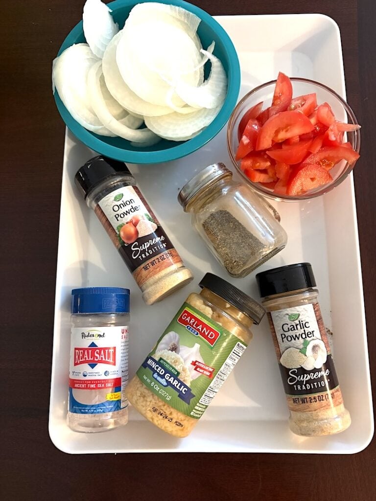 sliced onions, chopped tomatoes, and variety of seasonings for slow cooker chuck steak