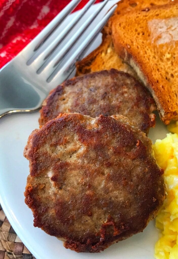 2 homemade turkey sausage patties on a plate with a fork
