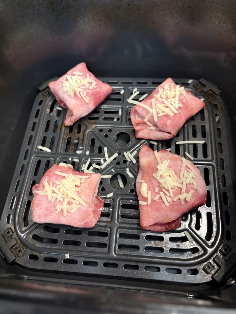 parmesan sprinkled on ham and cheese pockets in air fryer basket