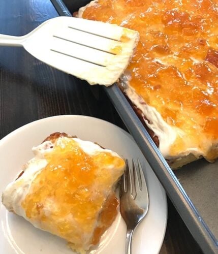 plate and pan of 2-ingredient peach cake with frosting and peach topping