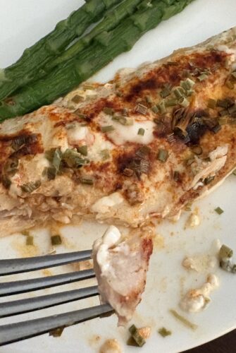 fork of fish hovered above a plate of baked ranch fish