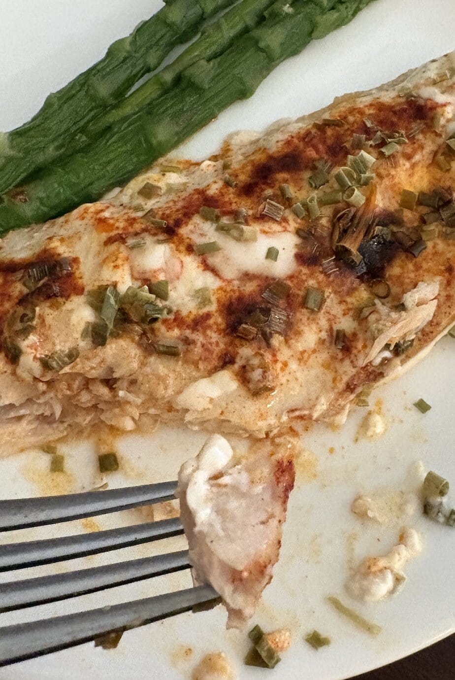 fork of fish hovered above a plate of baked ranch fish