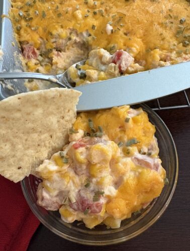 bowl and pan of cream cheese rotel corn dip with a tortilla chip