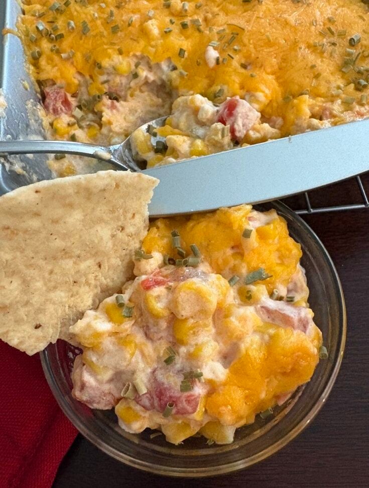 bowl and pan of cream cheese rotel corn dip with a tortilla chip