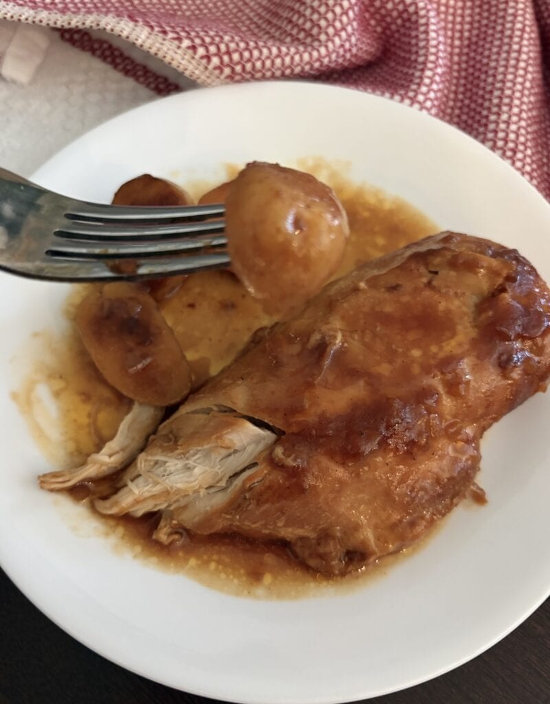 fork of potato over bbq chicken on a plate