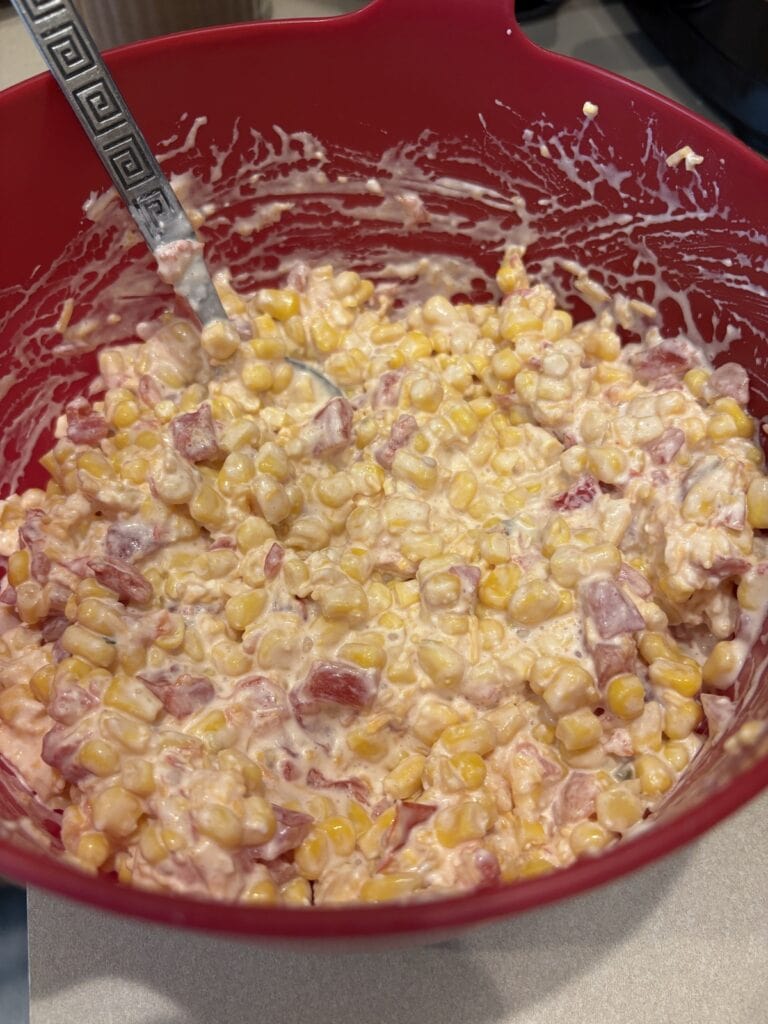 cream cheese rotel corn dip mixture in a bowl with a spoon