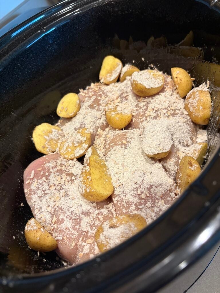 onion soup mix sprinkled over raw chicken and potatoes in crock pot