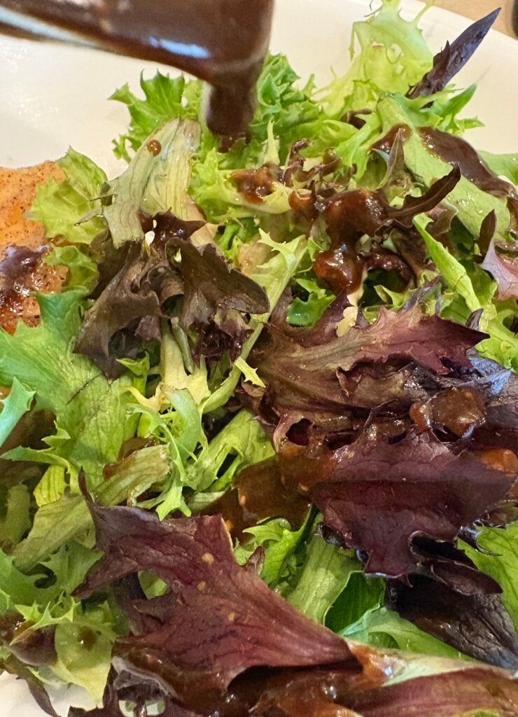 drizzling balsamic vinaigrette over spring mix salad