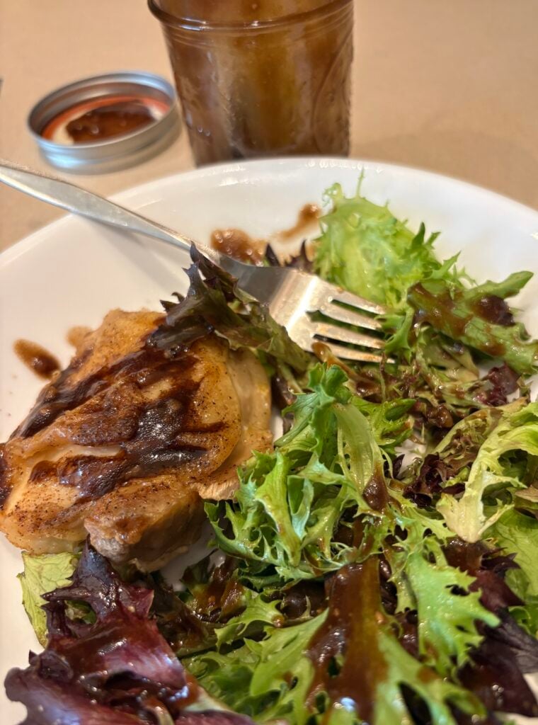 spring mix salad with chicken and jar of balsamic vinaigrette dressing