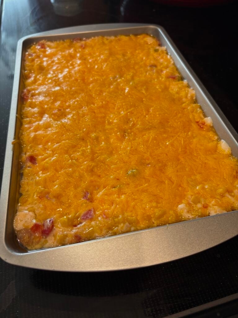 melted cheese over cream cheese rotel corn dip in a pan