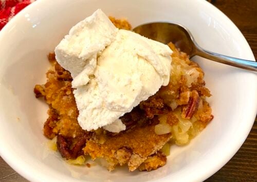 bowl of pineapple dump cake with vanila ice cream on top